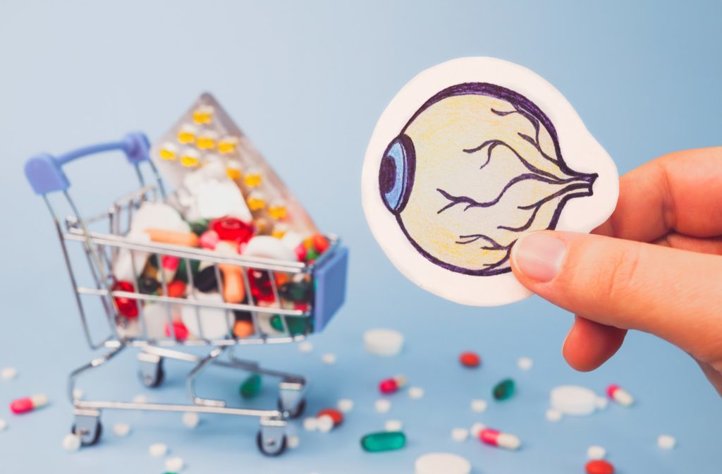 Hand holding drawing of eye in front of shopping cart filled with pills